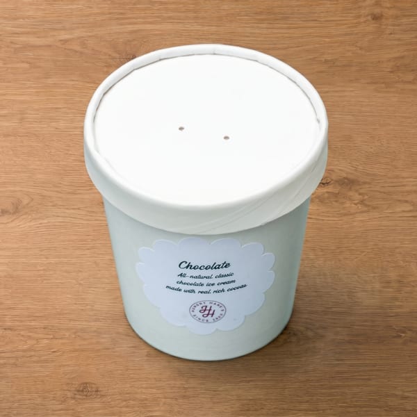 A white pint of Hungry Hane's chocolate ice cream sits on a wooden surface.