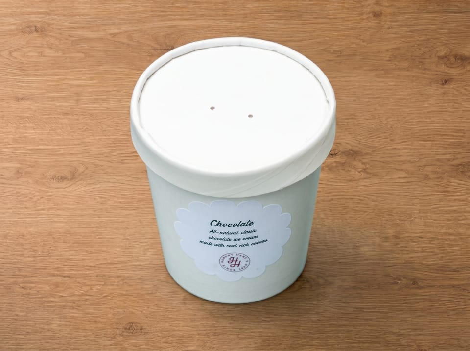 A white pint of Hungry Hane's chocolate ice cream sits on a wooden surface.