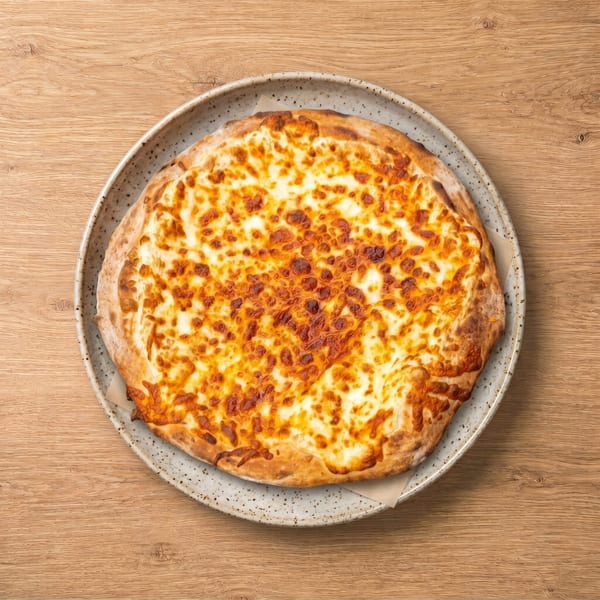 A round, golden-brown cheese pizza with a crispy crust, served on a speckled plate on a wooden table.