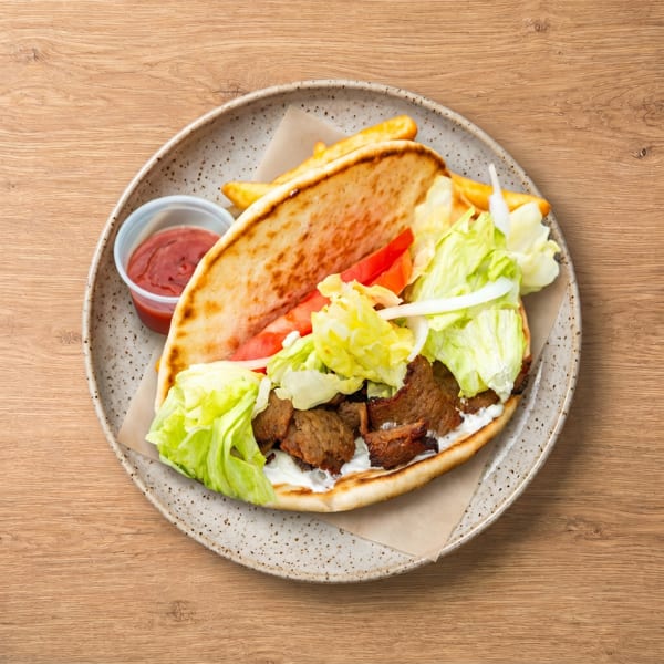 Gyro sandwich with meat, lettuce, tomatoes, onions, and tzatziki sauce, served with fries and ketchup.